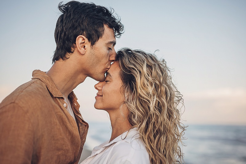 Couple in a loving embrace while walking outside on the beach.