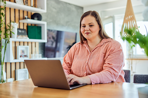 A woman wearing a pink sweatshirt schedules an appointment on her laptop