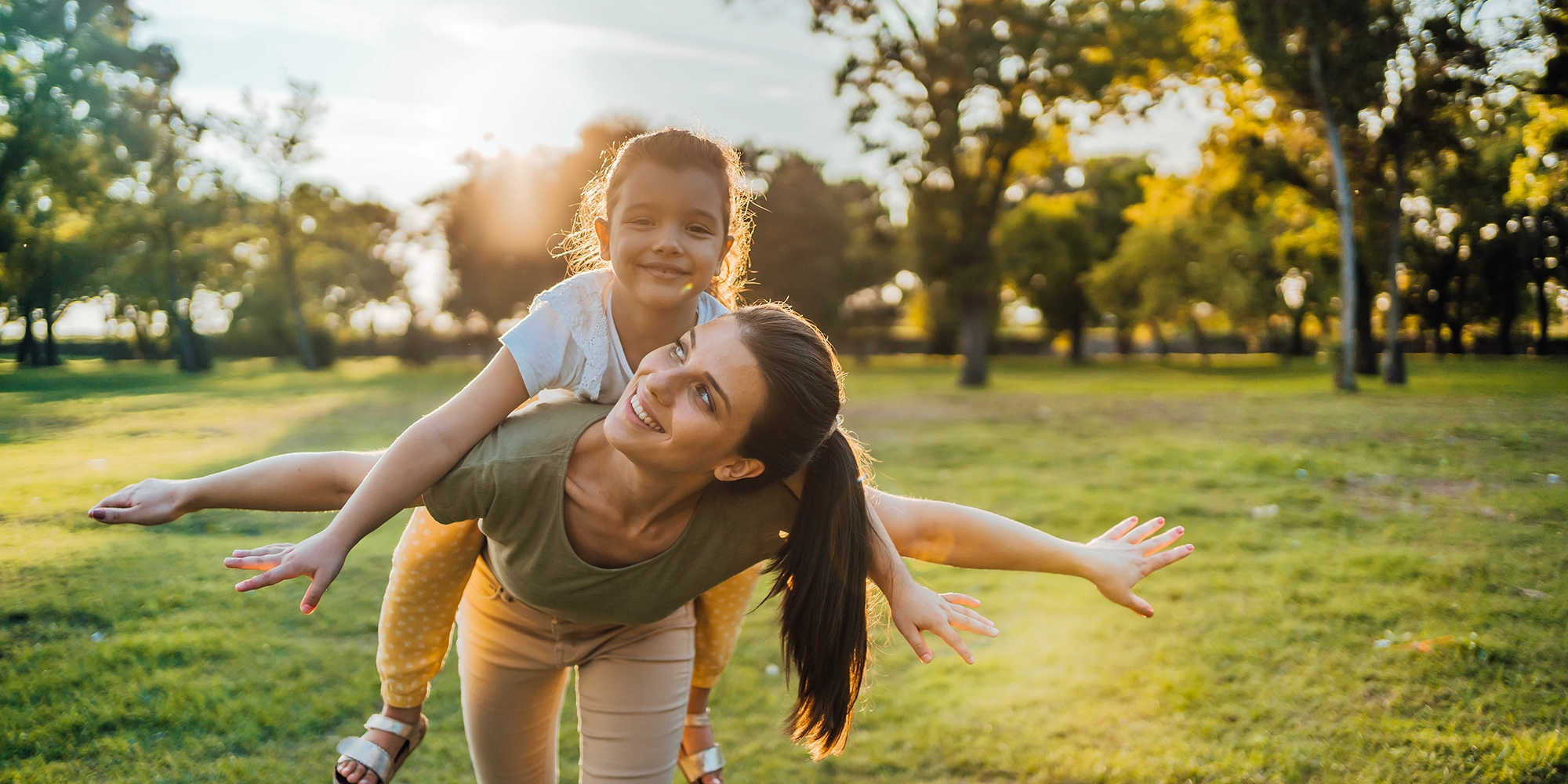 A mother gleefully gives a piggyback ride to her daughter