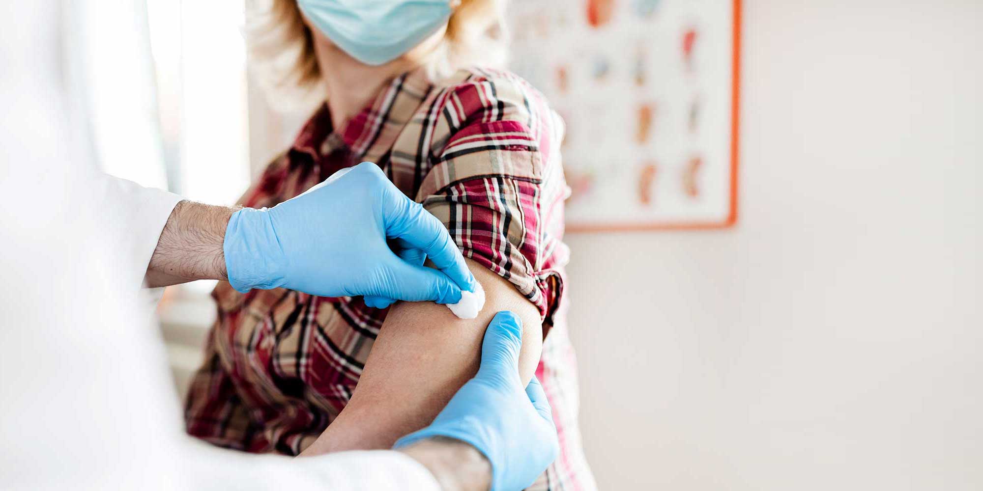 A patient's arm is being numbed in order to receive a vaccine shot