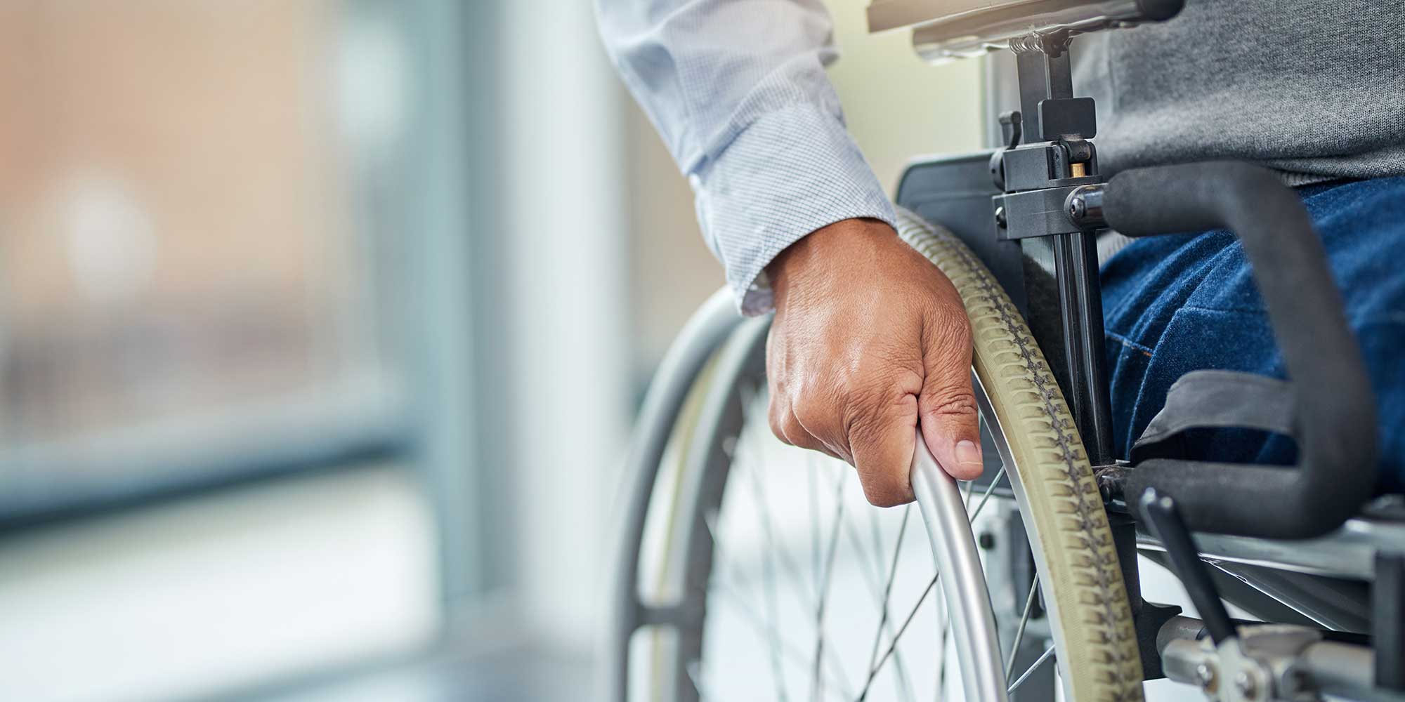 A zoomed in photo of a person's hand on the wheel of their wheelchair